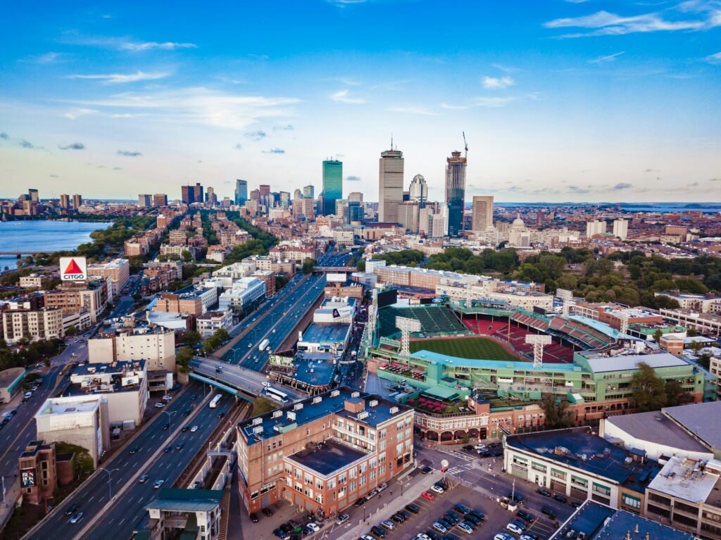 An aerial view of Boston, Massachusetts, featuring Fenway Park in the foreground and the downtown skyline in the background.