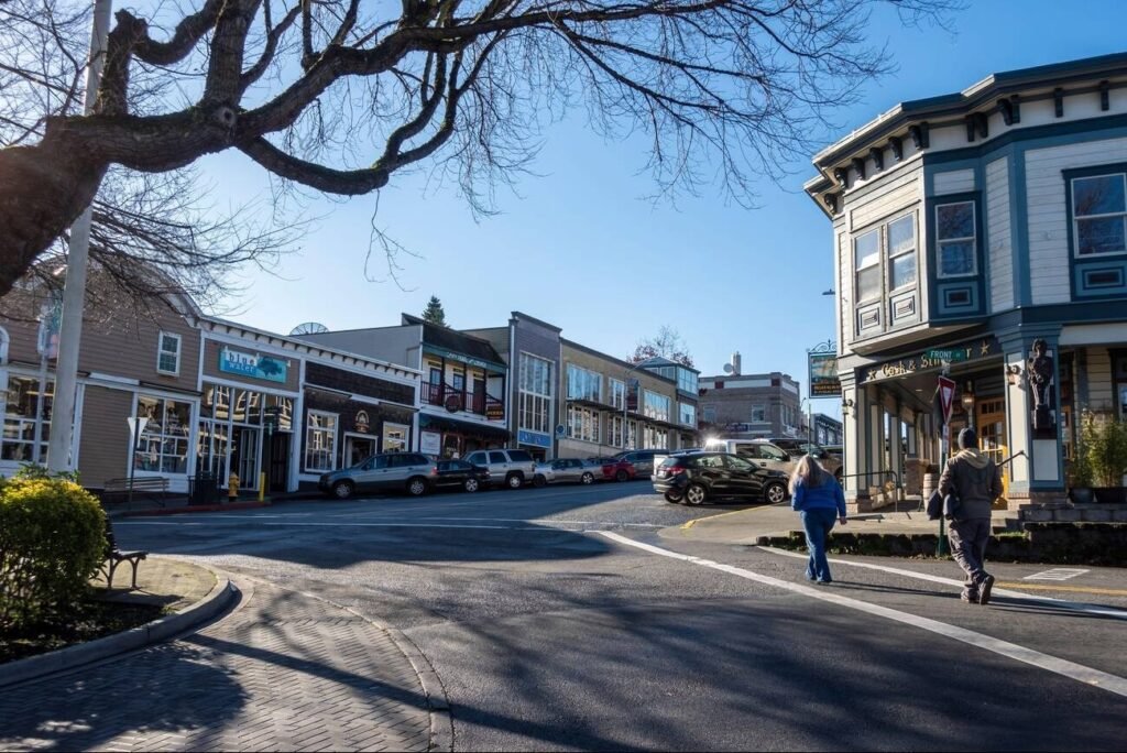 A sunny street corner in downtown Friday Harbor, Washington, with people crossing the street and historic storefronts.