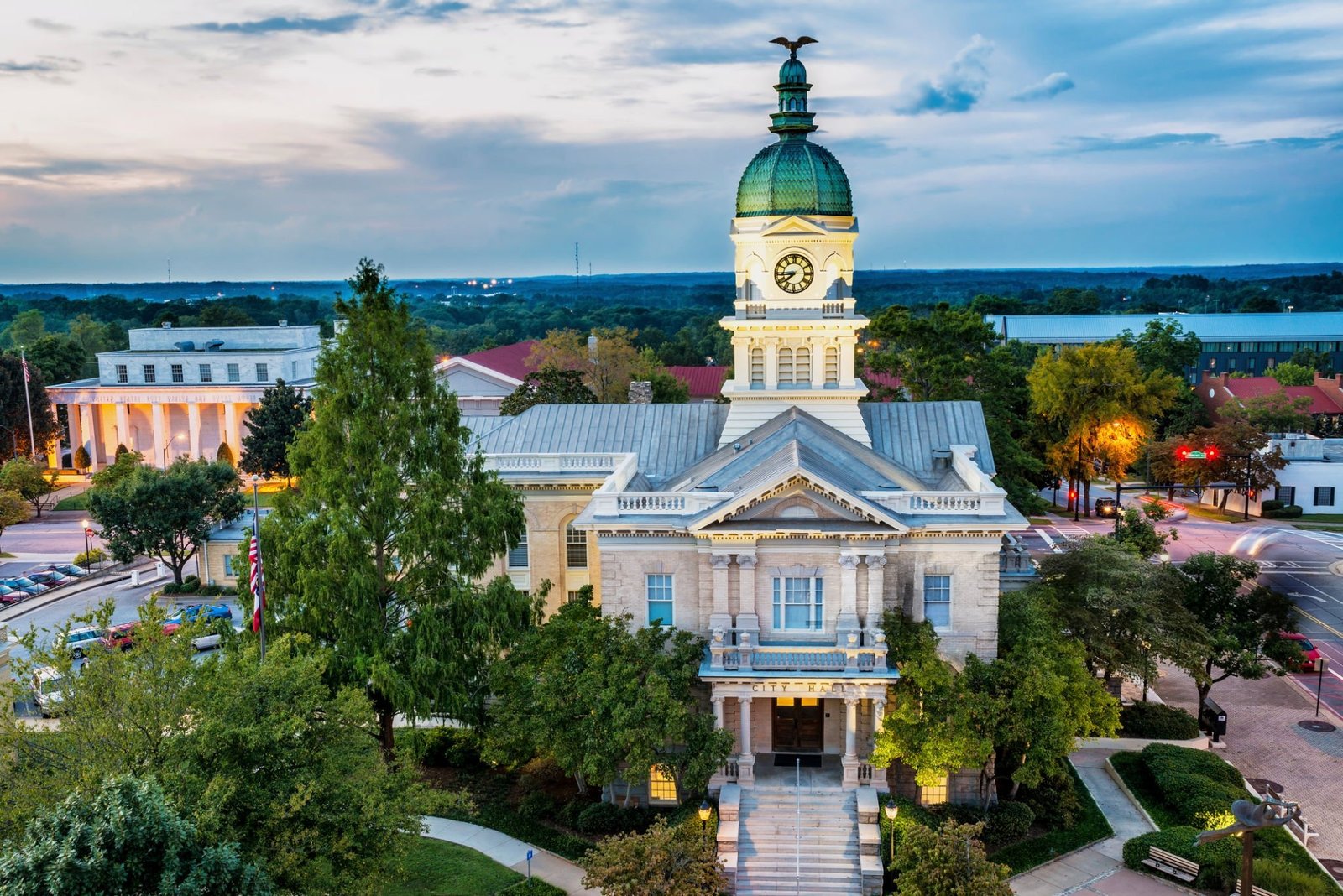 An aerial view of the historic Athens City Hall in Georgia at dusk, with its iconic clock tower and dome illuminated.