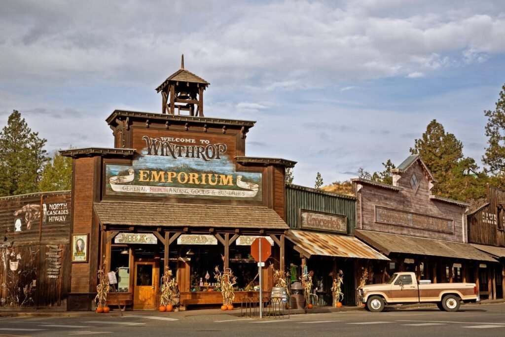 The Old West-themed storefronts of downtown Winthrop, Washington, including the "Winthrop Emporium," with a vintage pickup truck parked on the street.