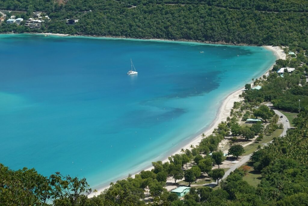 An elevated, panoramic view of the heart-shaped Magens Bay in St. Thomas, showing the white sand beach, turquoise water, and lush green hills.