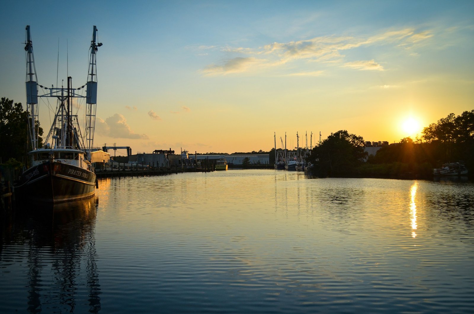 A shrimp boat docked in the harbor of Bayou La Batre, Alabama, during a golden sunset.