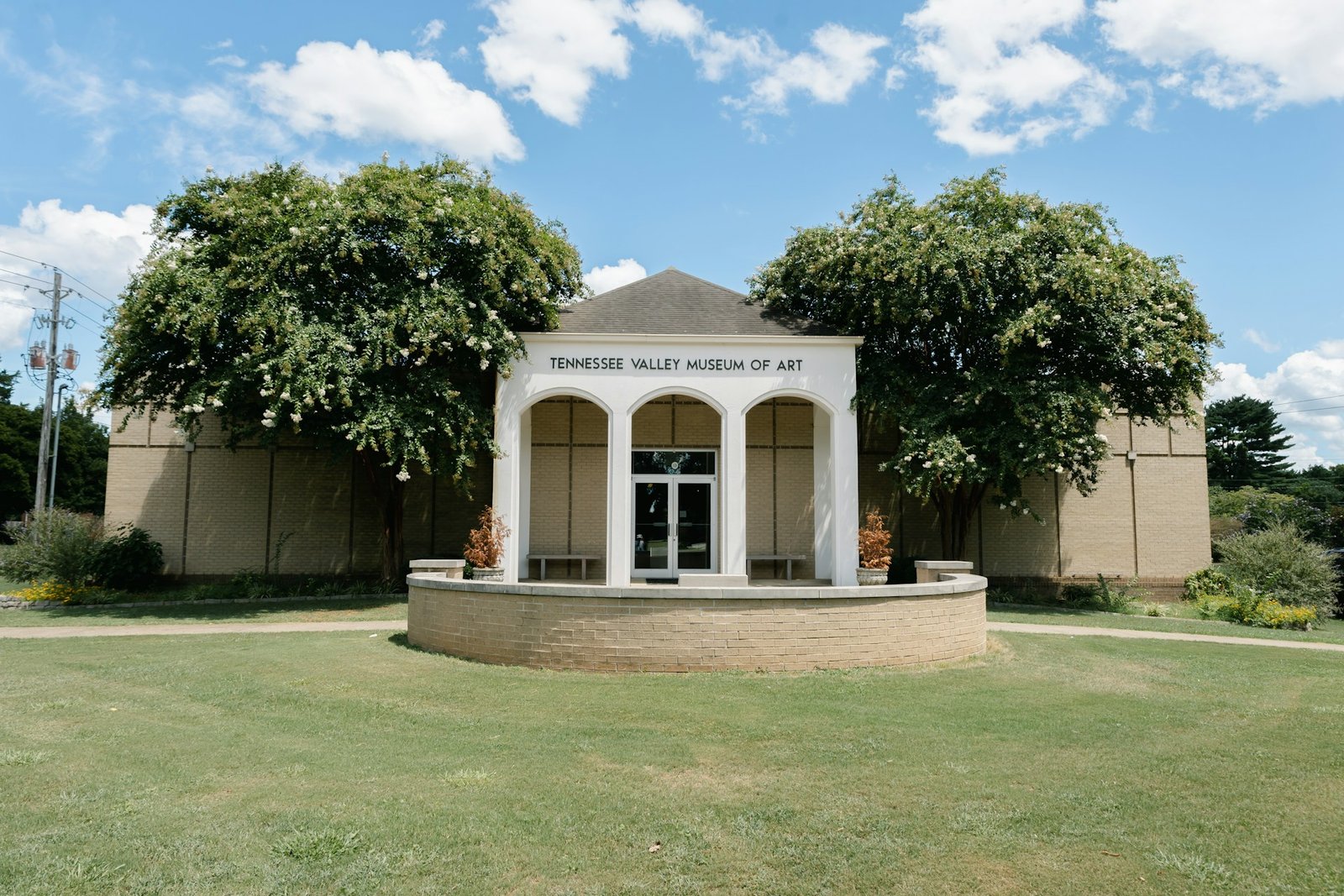 The entrance to the Tennessee Valley Museum of Art in Tuscumbia, Alabama, a building with a white arched portico flanked by two large trees.