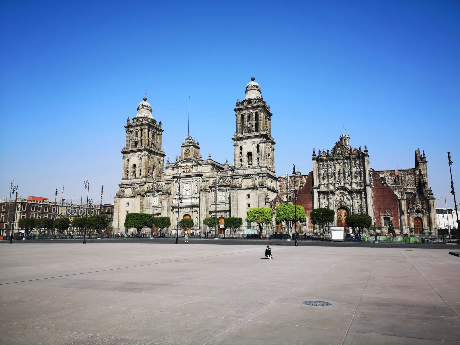 The Mexico City Metropolitan Cathedral viewed from across the vast Zócalo plaza on a clear, sunny day.