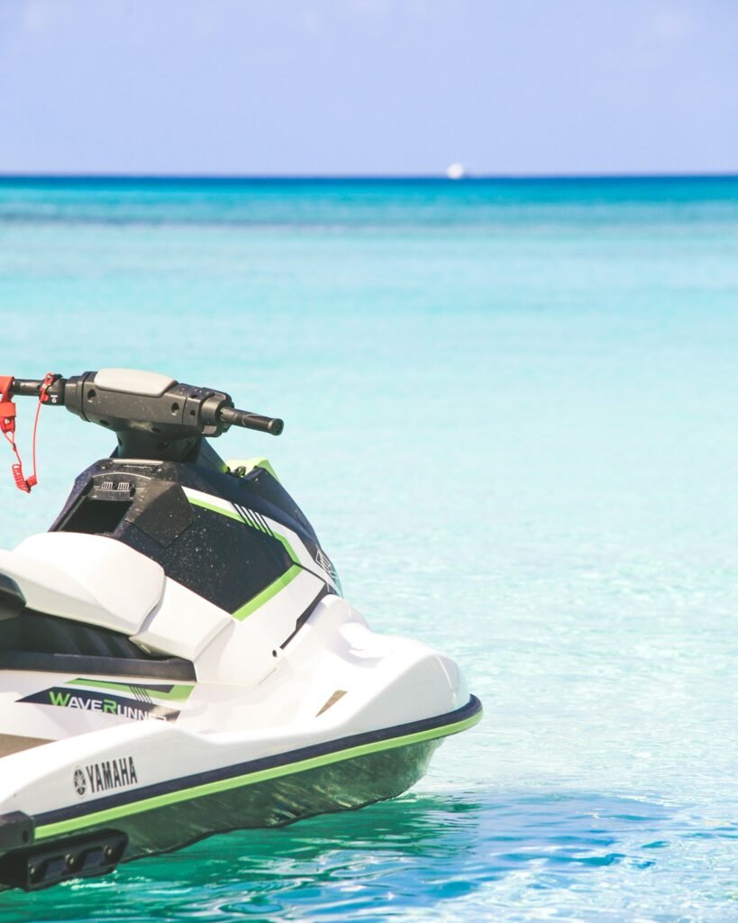 A Yamaha WaveRunner jet ski floating on the calm, crystal-clear turquoise water of Seven Mile Beach, Grand Cayman.