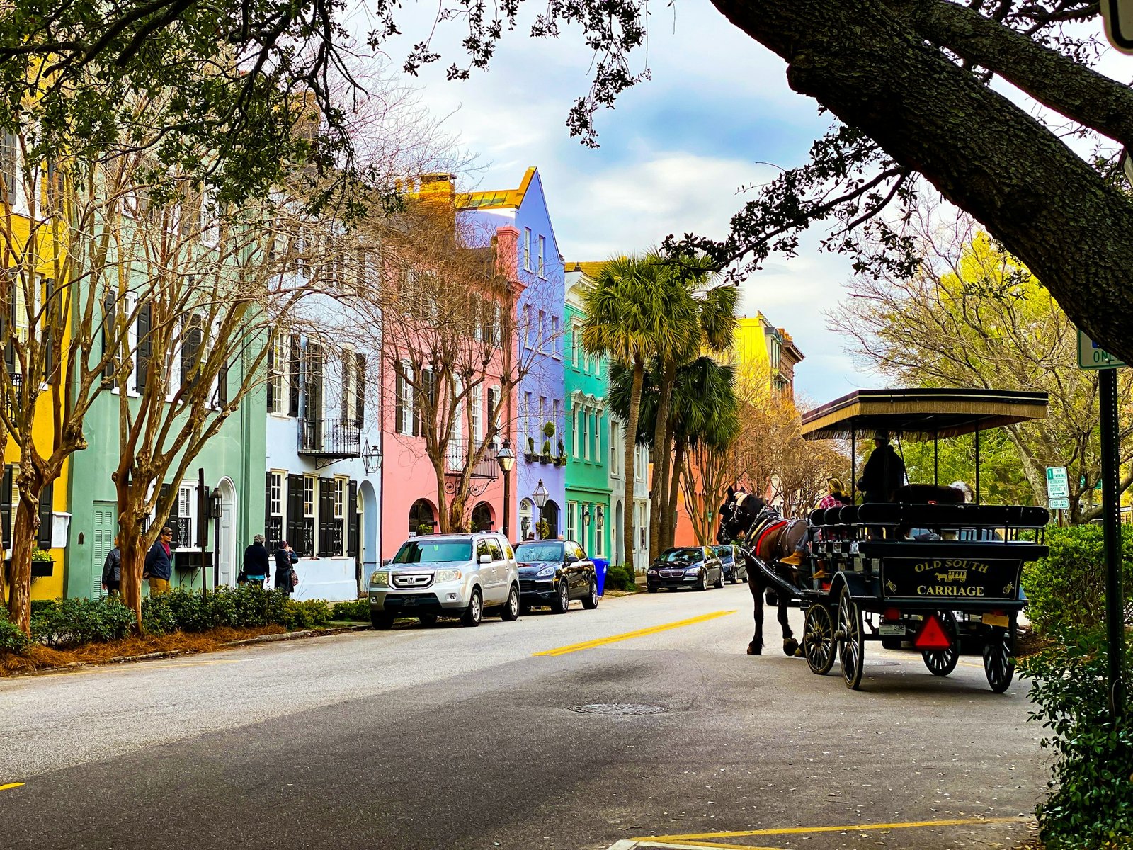 Horse-drawn carriage on a street lined with colorful historic buildings in Charleston, South Carolina.