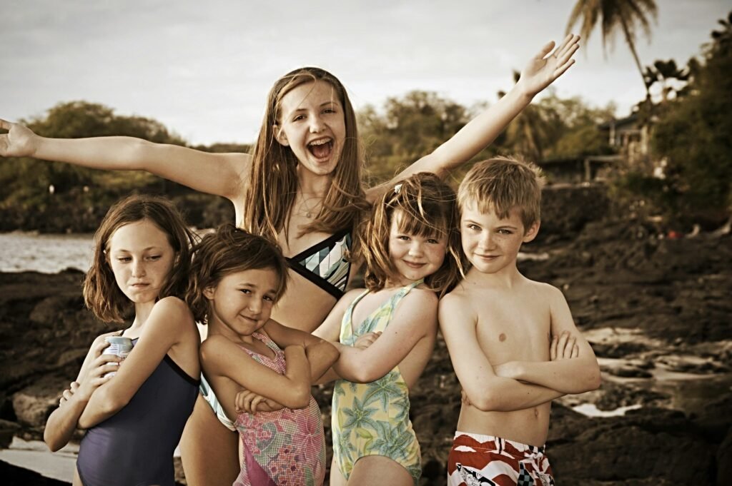 A group of five children in swimsuits posing together on a rocky beach, representing an adventurous family trip to Kiribati.