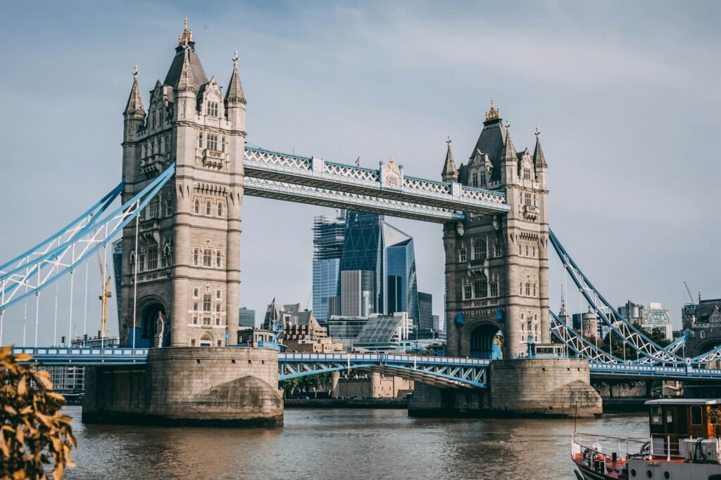The iconic Tower Bridge in London, with modern city skyscrapers visible between its historic towers, viewed from the River Thames.