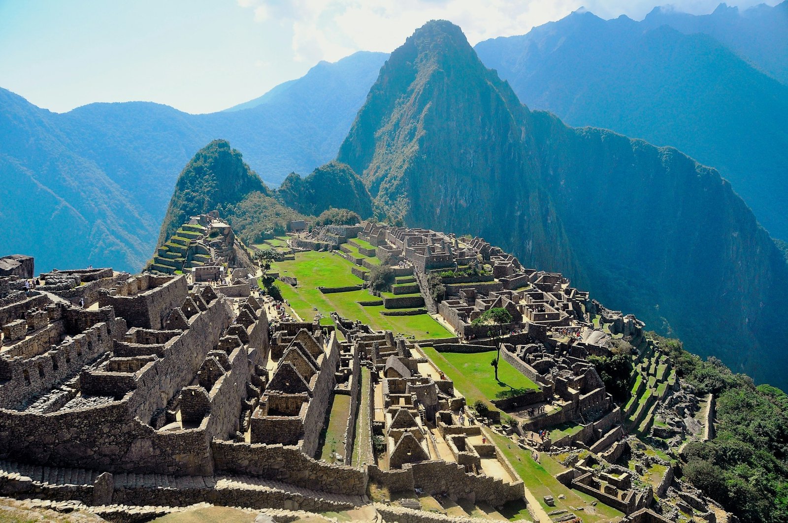 A classic, wide-angle view of the ancient Inca citadel of Machu Picchu in Peru, with the Huayna Picchu mountain in the background.