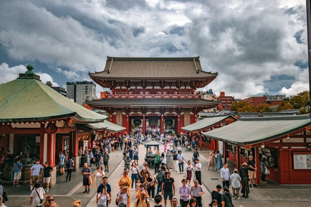 Asian Destinations : A large crowd of tourists at the historic Sensō-ji Temple in Asakusa, Tokyo, under a dramatic cloudy sky.