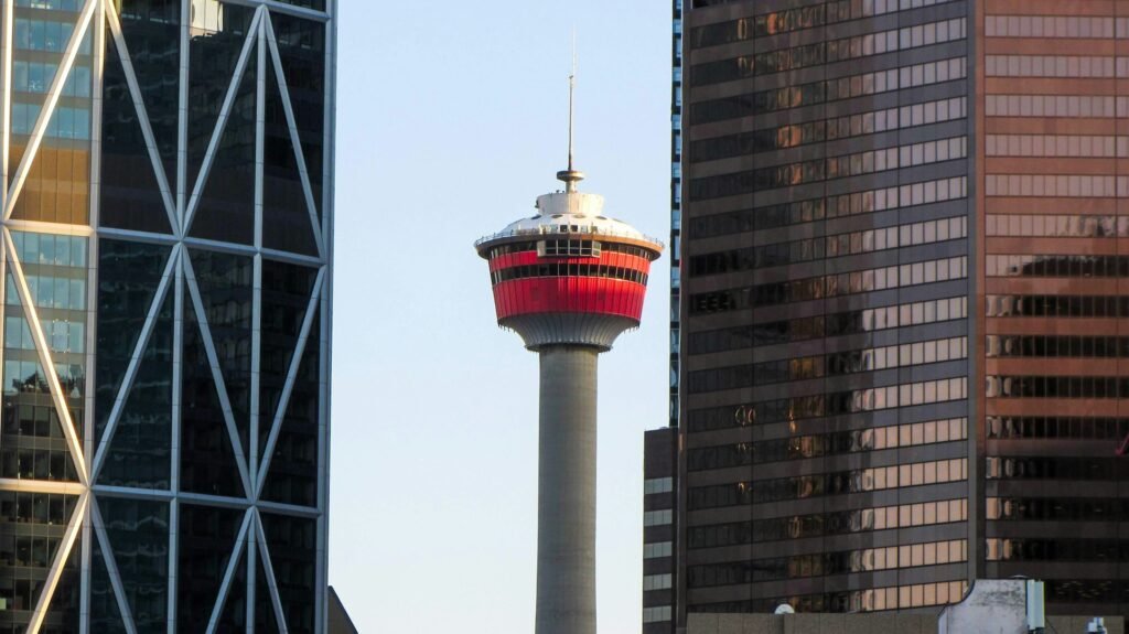 The iconic Calgary Tower, with its red observation deck, framed between two modern glass skyscrapers in downtown Calgary.