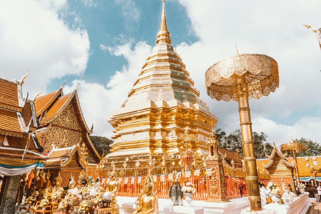 The magnificent golden stupa (chedi) of the Wat Phra That Doi Suthep temple in Chiang Mai, Thailand, under a blue sky.