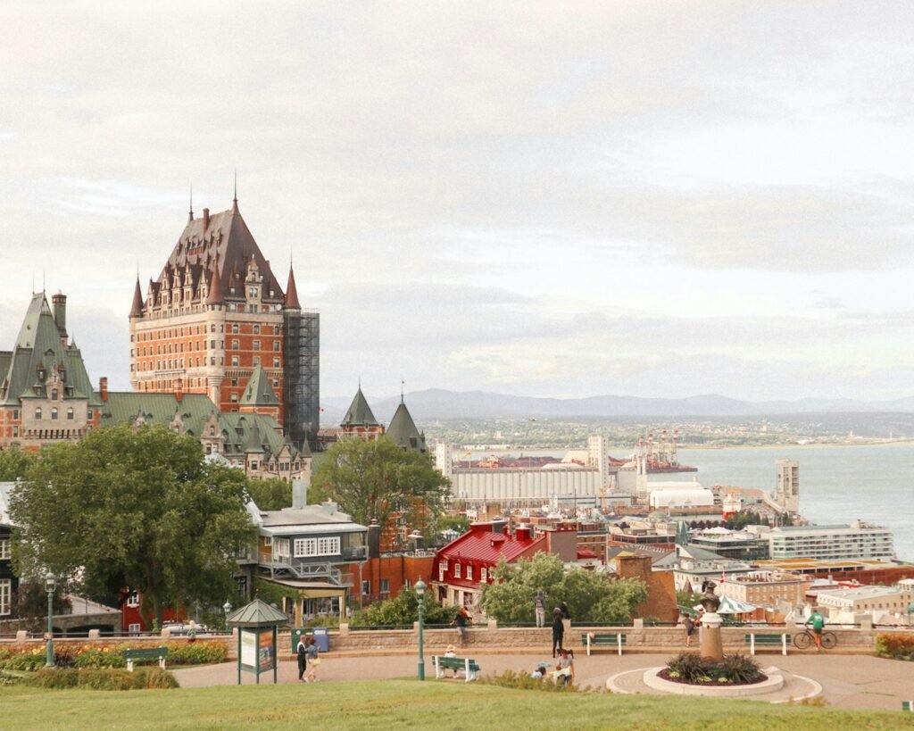 An elevated view of Quebec City, featuring the iconic Château Frontenac hotel overlooking the St. Lawrence River on an overcast day.