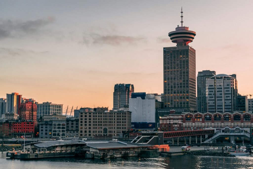 The Vancouver, British Columbia skyline at sunset, featuring the waterfront and the iconic Harbour Centre tower.