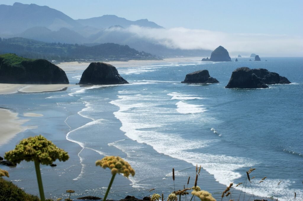 Haystack Rock rising above the ocean at Cannon Beach with coastal scenery and gentle waves.